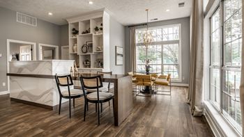 A kitchen with a white counter and a dining table with chairs